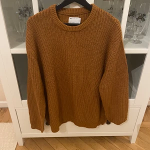 Brun stickad tröja från Asos - Säljer en snygg brun stickad tröja från asos. Tröjan har en klassisk rund hals och långa ärmar, perfekt för kyligare dagar. Den är i en härlig stickad kvalitet som ger en mysig känsla. Passar perfekt till både jeans och kjol!