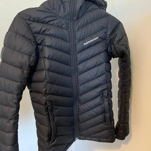 Svart dunjacka från Peak Performance - Snygg svart dunjacka från Peak Performance med dragkedja och huva. Den kom inte till användning hos mig så knappt använd.💕