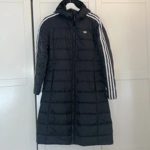 Adidas hooded premium slim jacket  - Snygg lång vår jacka med skärp i midjan endast använd fåtal gånger, i nytt skick. strl 36 pris kan diskuteras vid snabb affär 