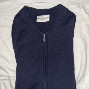 Mörkblå kofta från Bruun & Stengade - Säljer en stilren mörkblå kofta från Bruun & Stengade. Koftan har en praktisk dragkedja framtill och är tillverkad i ett mjukt material. Perfekt för kyligare dagar.