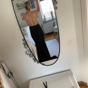 Svart långklänning med öppen rygg - Elegant svart långklänning med öppen rygg och smala axelband. Aldrig använd, köpte till balen men blev en annan istället. 