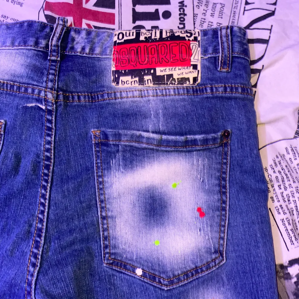 Snygga blå jeans från Dsquared2 med unika färgstänk i olika färger. De har en klassisk femficksdesign och en knappgylf. Perfekta för en trendig look! OBS! Storleken som står stämmer inte, det är storlek 48 igentligen för att byxorna inte är äkta, det är därför dom är mindre i storlek än vad det står (storlek 48) är dom. Farkut & Housut.