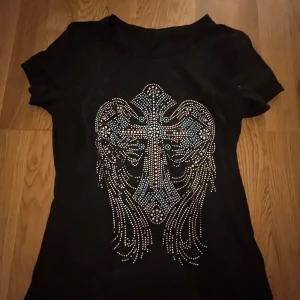 Svart t-shirt med glittrigt mönster - Snygg svart t-shirt med ett glittrigt mönster framtill. Formen är jättesnygg och den är mycket bekväm💓💓