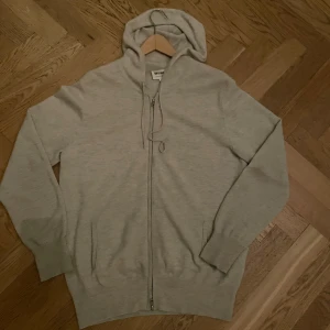 Grå hoodie från Soft Goat - Säljer en stilren grå hoodie från Soft Goat. Den är tillverkad i mjukt material och har en dragkedja framtill. Perfekt för en avslappnad look. Hör av dig vid intresse!