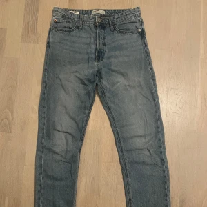 Blå jeans från Jack & Jones - Säljer ett par klassiska blå jeans från Jack & Jones. De har en loose fit och är tillverkade i denim med en knapp i midjan. Perfekta för en avslappnad stil.