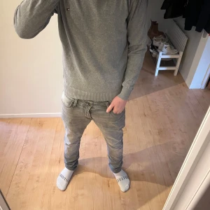 Grå tröja från Tommy Hilfiger - Säljer en stilren grå tröja från Tommy Hilfiger med v-ringning. Tröjan har långa ärmar och ribbade muddar vid ärmslut och nederkant. Perfekt för en avslappnad men snygg look skick 8/10