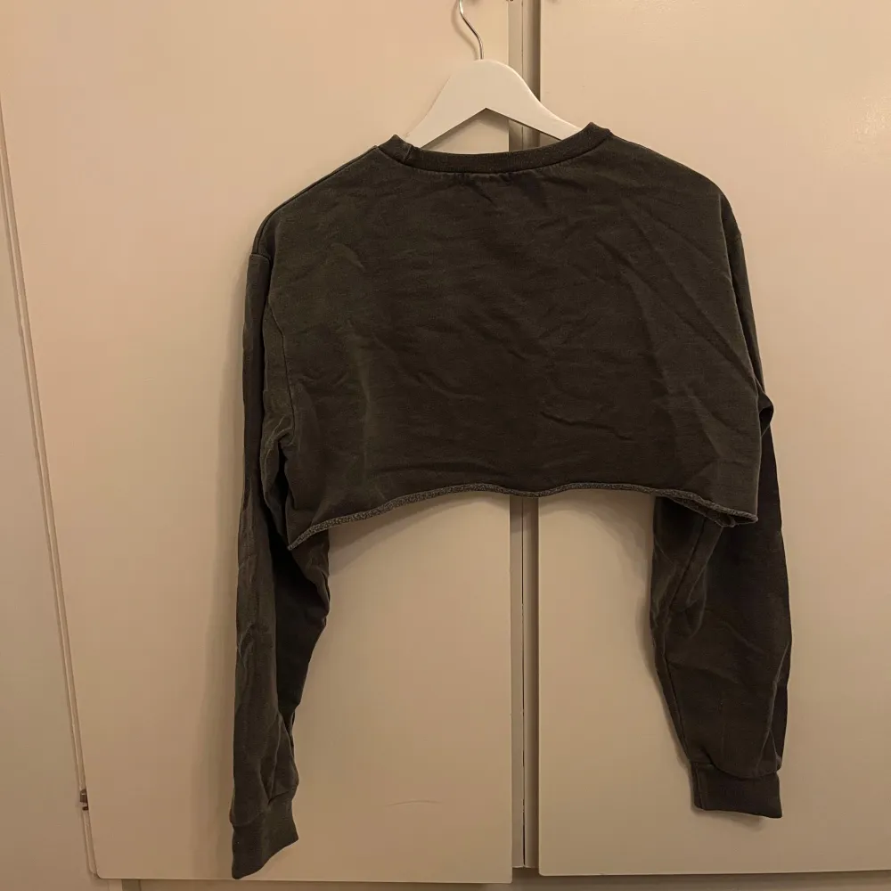 Säljer en grå croppad tröja. Tröjan har långa ärmar och en avslappnad passform. Perfekt för en casual look. I ett mycket bra skick!. Neuletakit & Villapaidat.