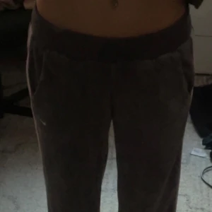 Grå mjukisbyxor från Nike - Säljer ett par grå mjukisbyxor från Nike med en vit logga på benet. Byxorna har en loose passform och är tillverkade i ett mjukt material, perfekt för en avslappnad stil.