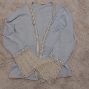 Gullig kofta med spettsdetaljer - Säljer jättegullig coquette kofta💞                                                  Säljer en ljusblå kofta med vackra spetsdetaljer och broderade blommor. Koftan har långa ärmar och en öppen design framtill. Perfekt för en elegant och romantisk stil.