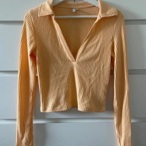 Beige ribbad tröja - Snygg beige ribbad tröja med djup v-ringning och långa ärmar. Perfekt för en stilren look.