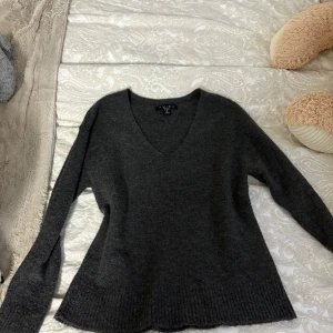 Mörkgrå tröja från Amisu - Säljer en stilren mörkgrå tröja från Amisu med v-ringning. Tröjan har långa ärmar och är tillverkad i ett mjukt material som passar perfekt för kyligare dagar. Perfekt för en avslappnad och bekväm look.