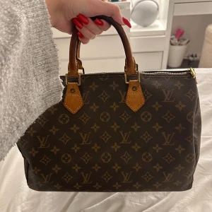 Louis Vuitton Speedy 35 Monogram Canavas - Louis Vuitton Speedy 35 Monogram. Säljer nu denna pågrund av att jag tröttnat på den så någon annan kan få ta över den! Väskan har två handtag och en ficka inuti.❗️Notera att jag har suttit ditt blixtlåset själv då väskan kom utan ett.❗️Notera att läder detaljerna på båda sidorna gått sönder så därav klippta. Väskan är köpt på vinted och är i jätte fint skick och inga defekter förutom det jag nyss skrev. Nypris 19.800kr säljer för 4000kr