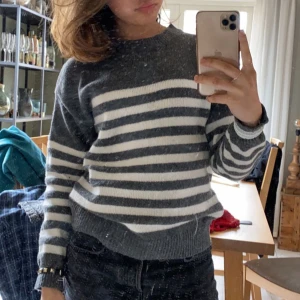 Grå och vit randig tröja - Säljer en mysig grå och vit randig tröja med långa ärmar. Perfekt för kyligare dagar. Tröjan har en klassisk design med ribbade muddar vid ärmslut och nederkant. (Köpt tidigare här på Plick)