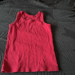 Röd ärmlös linnetopp - Säljer en enkel och stilren röd ärmlös linnetopp. Perfekt för varma sommardagar eller som ett basplagg i garderoben. Tillverkad i mjukt material för extra komfort.