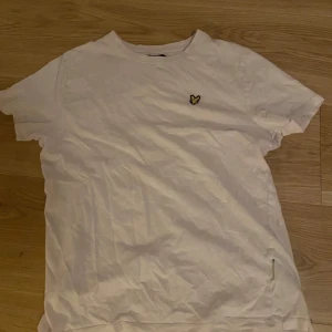 Rosa t-shirt från Lyle & Scott - Säljer en rosa t-shirt från Lyle & Scott med deras ikoniska logga broderad på bröstet. Perfekt för en avslappnad look. Kortärmad och i mjukt material.
