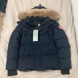 Canada Goose Wyndham - Säljer en mörkblå dunjacka från Canada Goose, modell Wyndham. Väldigt bra kvalitet och bara använt ett par gånger, säljer då den inte passar. Pris går definitivt att diskutera!