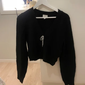 Kofta - Kofta med rosett i strass framtill. Superfint skick ifrån H&M.