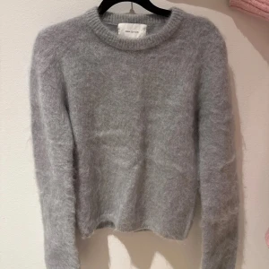 Grå mohairtröja från H&M Edition - Säljer en supermjuk och fluffig grå tröja från H&M Edition. Tröjan är tillverkad i en blandning av mohair och ull, vilket gör den perfekt för kyliga dagar. Den har en klassisk rund hals och långa ärmar. Perfekt för att hålla sig varm och stilren!