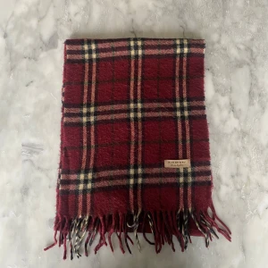 Vinröd burberry halsduk  - Skick: 8/10. Halsduken är i bra skick och har inga defekter. Mått: 147cm x 29cm