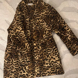 Leopardmönstrad pälsjacka - Säljer en så snygg quiltad leopardmönstrad kappa🐆✨ Jackan har långa ärmar och dragsko i midjan för en snygg passform (går även att knyta med snörena) Sparsamt använd storlek S