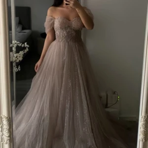 Glittrig champagne Klänning/balklänning/bröllop - Glittrig champagne klänning med en vacker pärltopp med snörning baktill. (Använd en kväll)  •Nypris:7500kr säljer för 3800kr •storlek:34/36 kan passa en liten 38 pga snörningen. Man får även med klädöverdraget från butiken klänningen köptes ifrån. 