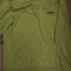 Grön hoodie från Carhartt - Säljer en snygg och bekväm grön sweatshirt från Carhartt. Perfekt för både vardag och chill. Den har en klassisk passform och är i storlek S. Tröjan är som nytt skick och redo för nya äventyr! 💚