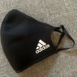 Svart munskydd från Adidas - Säljer ett svart munskydd från Adidas. Det är helt nytt, aldrig använt. 