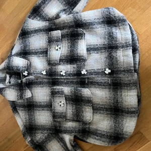 Rutig jacka från Gina Tricot - Säljer en superfin rutig jacka från Gina Tricot i  M. Den har en klassisk svart och grå färgkombination med stora knappar framtill. Jackan är långärmad och har en skön, lite oversized passform. Perfekt för höst och vår! Köpt för 799 säljer för 599