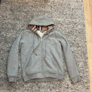 Säljer min Burberry zip up hoodi har använt den typ 2-3 gånger för att den passar mig inte längre och skulle vilja sälja den. Priset kan diskuteras och svarar på alla frågor om hoodin - En grå burberry zip up hoodi som är storlek M men passar mer personer som har storlek S. Perfekt hoodi för vintern för den är varm och jätte tjockt material. 