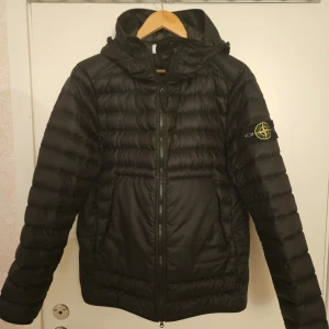 Stone Island Jacka - Denna Stone Island-jacka i nyskick, fylld med fjäder och dun, kombinerar värme och stil. Priset går o diskutera vid snabb affär.