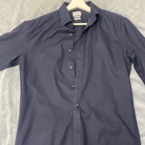 Mörkblå skjorta från Selected Homme - Säljer en stilren mörkblå skjorta från Selected Homme i slim fit. Skjortan har långa ärmar och knappar hela vägen ner. Perfekt för både vardag och fest! Materialet är lätt att stryka och känns bekvämt mot huden. Passar utmärkt till både jeans och kostymbyxor. 🕺