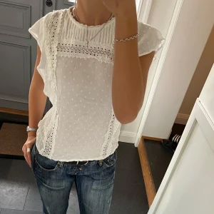 Vit spetstopp - Vit topp med spets och volanger från Evermee i storlek 36. Fint skick. Använd gärna köp nu!