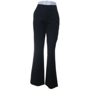 Svarta kostymbyxor med bootcut - Säljer ett par eleganta svarta kostymbyxor med en snygg bootcut-stil. De är högmidjade och perfekta för både kontoret och festliga tillfällen. Byxorna har en klassisk look som aldrig går ur tiden.