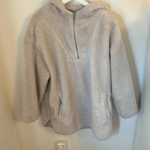 Beige fleece hoodie - Mysig och varm beige hoodie i fleece-material. Perfekt för kalla dagar med sin mjuka och fluffiga känsla. Den har en dragkedja framtill och en stor huva för extra komfort. Passar perfekt för höst och vinter!