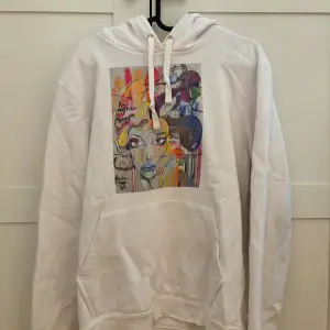 Säljer en supercool vit hoodie från The Cool Elephant med ett färgglatt tryck på framsidan. Hoodien har en stor ficka fram och justerbar huva med snören. 