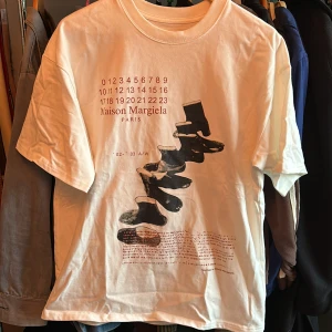 Maison Margiela T-shirt - Hej, säljer min Maison Margiela T-shirt med Tabi motiv. Den är knappt använd och har bara legat. Den är storlek 46/M men har en lite oversized passform. Vid frågor eller funderingar är det bara att skriva!