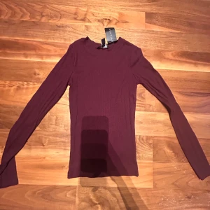 Vinröd ribbad tröja från New Look - Säljer en snygg vinröd ribbad tröja från New Look. Den är långärmad och perfekt för höst och vinter. Tröjan är i storlek XS och har en tight passform. Superfin att ha till både vardags och fest!