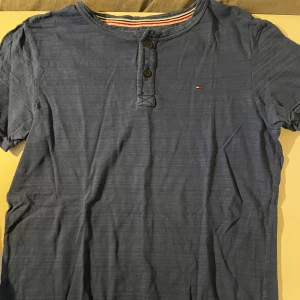 Tommy Hilfiger t-shirt - Blå Tommy t-shirt i bra skick dock några små hål se bild 4 och 5 därför till ett billigare pris! Storlek=176