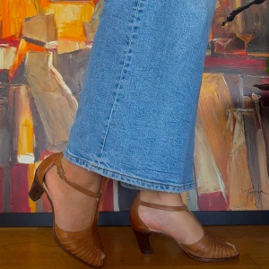 Bruna klackskor i skinn - Säljer ett par snygga bruna klackskor i skinn. De har en elegant design med en öppen tå och remmar runt ankeln. Perfekta för både vardag och fest! Klacken är stabil och ger en skön höjd utan att bli obekväm. Passar perfekt till jeans eller en dress!