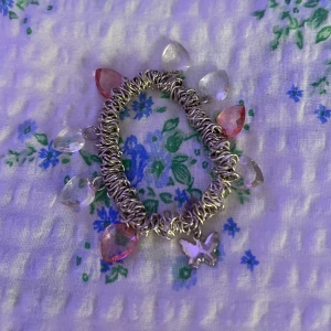 Sött armband med hjärtformade berlocker - Det här är ett superfint armband med hjärtformade berlocker i rosa och genomskinliga färger. Armbandet har en kedja i silverfärg och en liten fjärilsberlock som hänger i mitten😍🦋 