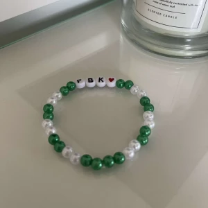 Pärlarmband med bokstäver och hjärta - Säljer ett superfint armband med gröna och vita pärlor. Det har bokstäverna 'FBK' och ett rött hjärta i mitten. Perfekt för att ge lite färg till din outfit! 💚🤍❤️
