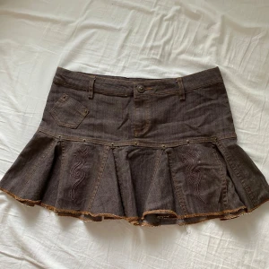 Jeanskjol brungrå  - Brungrått jeanstyg. Lågmidjad jeanskjol. Midjemått ca 41. Längd 32 cm. Bra skick 