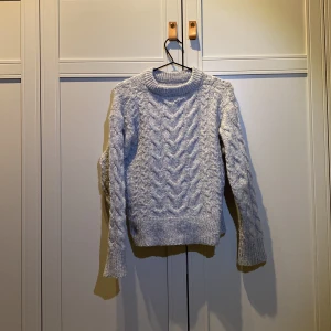 Grå stickad tröja från Gina tricot - Den här gråa tricksade tröjan är en väldigt fin tröja till vardagen! Den är i bra skick och har inte blivit använd så mycket! Hör av er till mig om ni är intresserade🫶🏻🫶🏻