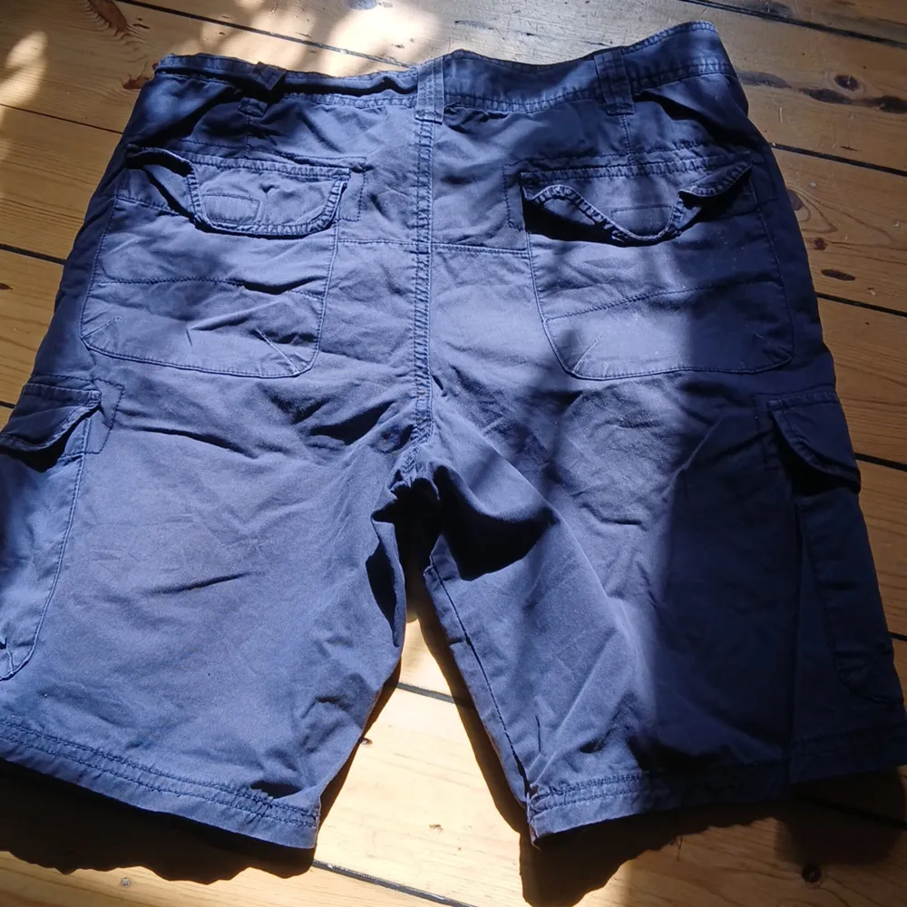 Snygga blåa cargo shorts köpta i spanien för några år sedan, min brors gamla och har varit ganska välanvända men har bara legat i garderoben i några år så dam kan förekomma. Inga bilder på skickas. Midjemått rakt över 39cm, innrebenslängd 24cm💕. Shorts.