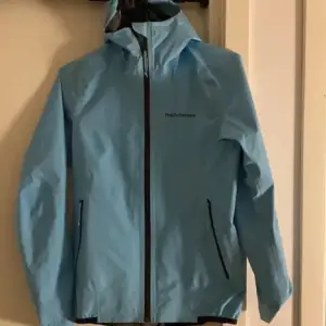 Peak performance Goretex Skaljacka, modell ”W GoreTex PAC Jacket  Fin ljusblå färg samt kvalitativa egenskaper såsom vattentät, vattenpelare 28 000mm, vindtät, packbar, god andningsförmåga etc.  Storlek xs dam Nypris 3200kr