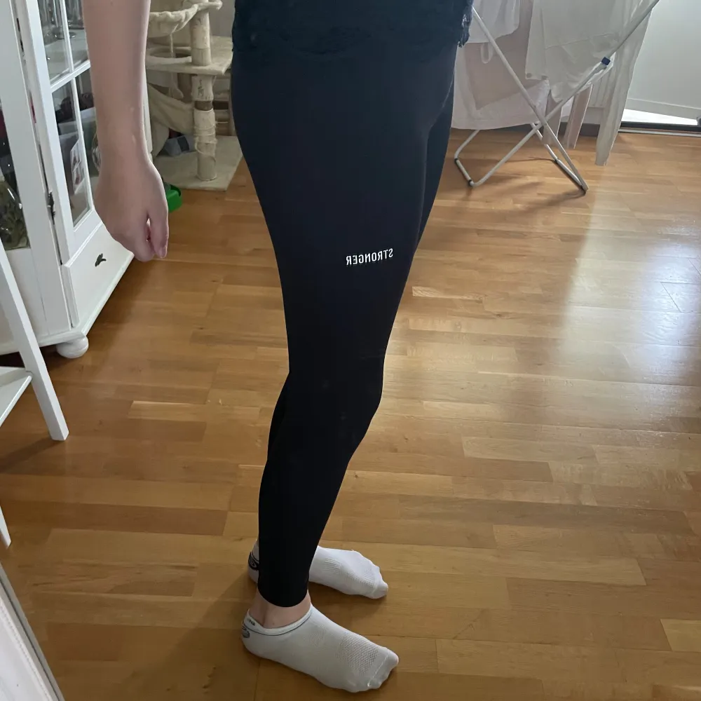 Säljer ett par svarta tights från Stronger. De är tighta och perfekta för träning eller en chill dag hemma. Superbekväma och stretchiga, med en hög midja som sitter på plats. Passar till allt och är ett måste i garderoben! storlek xs. stronger texten är lite sliten men inget man tänker på 💓. Jeans & Byxor.