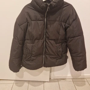 Svart pufferjacka med dragkedja - Säljer en svart pufferjacka som är perfekt för kalla dagar. Jackan har en dragkedja framtill och är långärmad. Den är varm och skön, idealisk för vinter och höst. Passar bra till både vardag och utomhusaktiviteter.