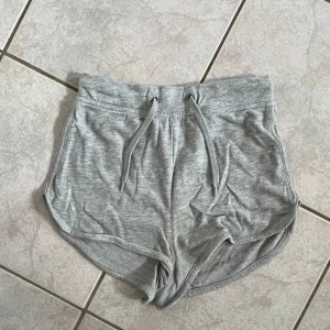 Grå shorts från Bik Bok - Säljer ett par grå shorts från Bik Bok i storlek XS. De är superbekväma med en mjuk resårmidja och snörning framtill. Perfekta för en avslappnad dag hemma eller en snabb tur till gymmet. Materialet känns som bomull och de har en loose passform. skriv vid frågor💗