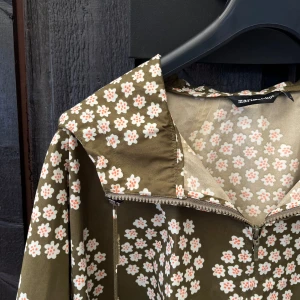 Marimekko Rain Jacket/Poncho with Floral Pattern - Like New - This rain jacket/poncho from Marimekko has a floral pattern, makes it perfect for rainy days while still being stylish enough for everyday wear. It has side buttons that allow it to open completely or to shape arms. Generously sized to fit backpack. 