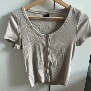 Beige t-shirt med knappar från Gina tricot - Bra skick knappt använd